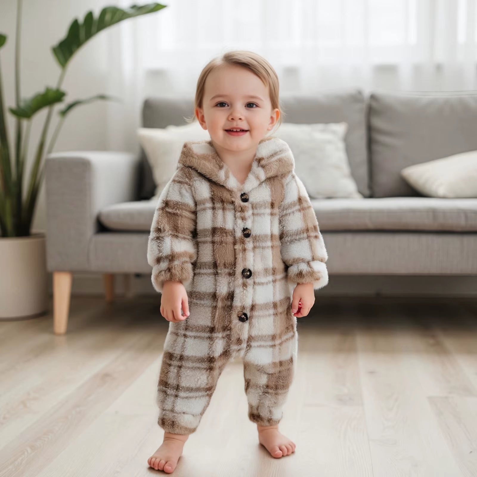 Toddler standing in living room wearing cream plaid romper with hood