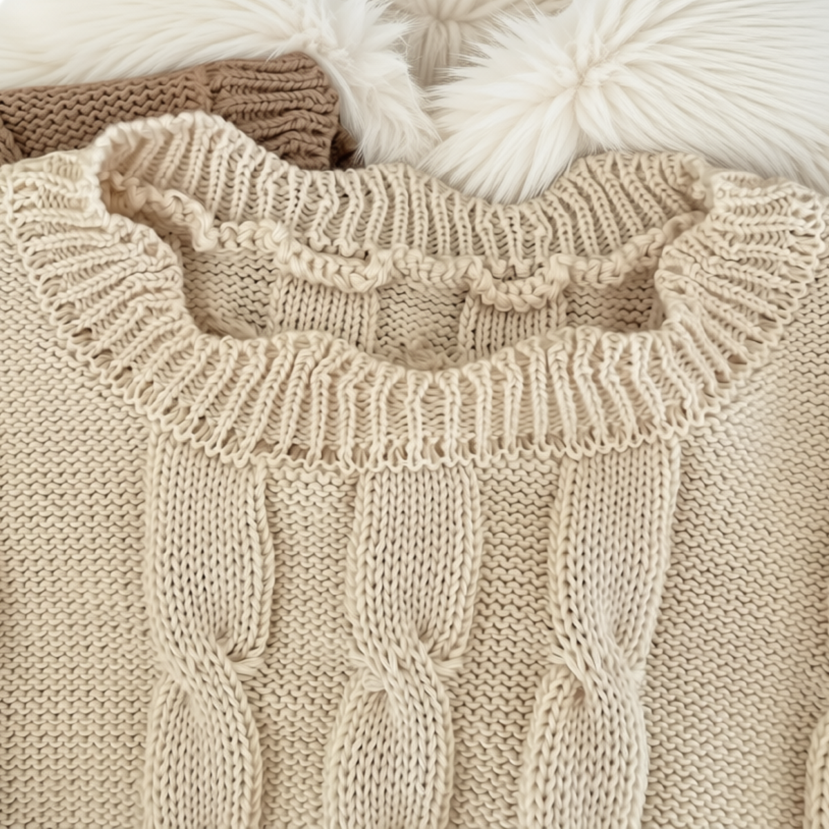 Close-up of cream girls’ cable-knit vest showing the ribbed neckline and detailed cable-knit texture