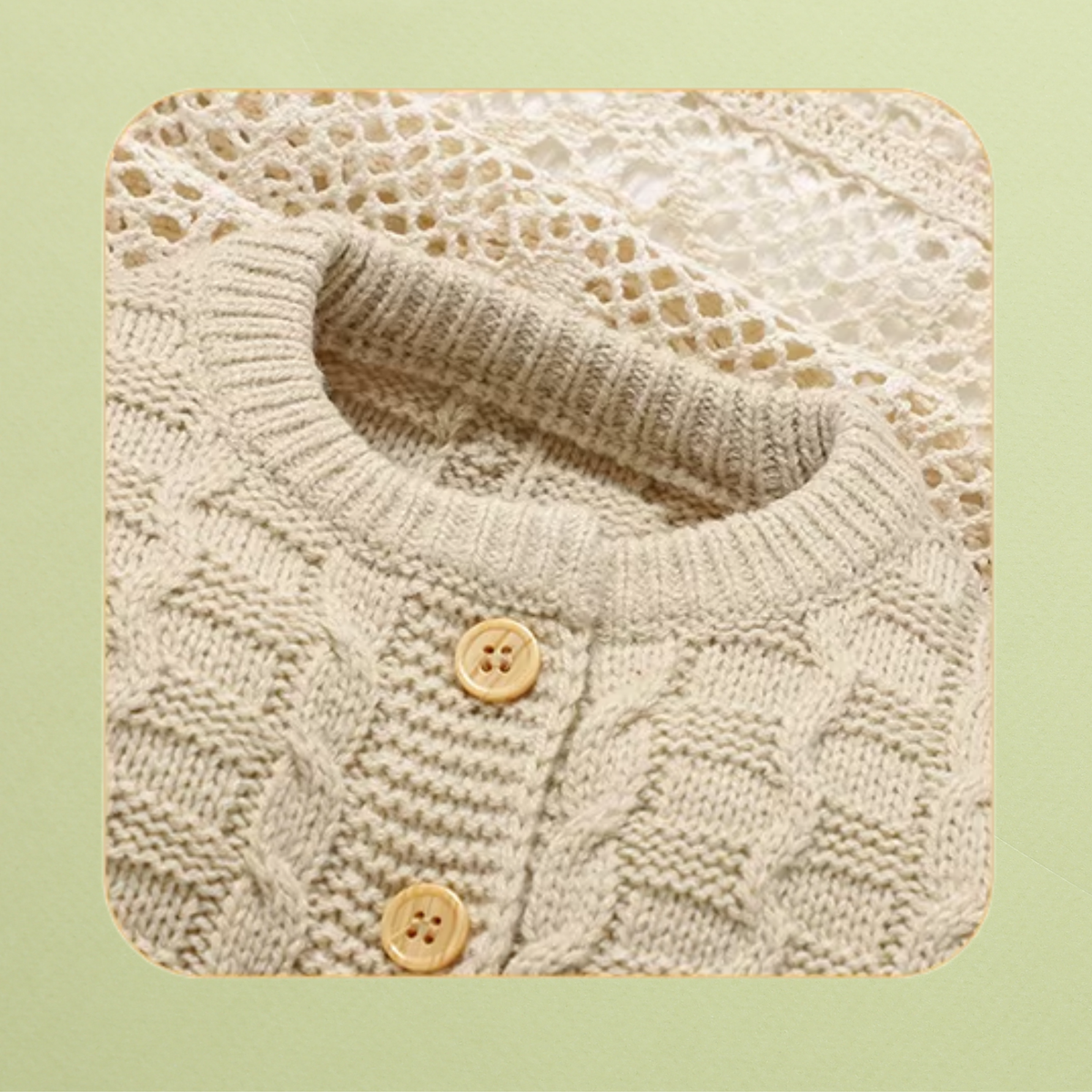 Close-up of cream knit baby cardigan neckline with wooden buttons and cable knit detail
