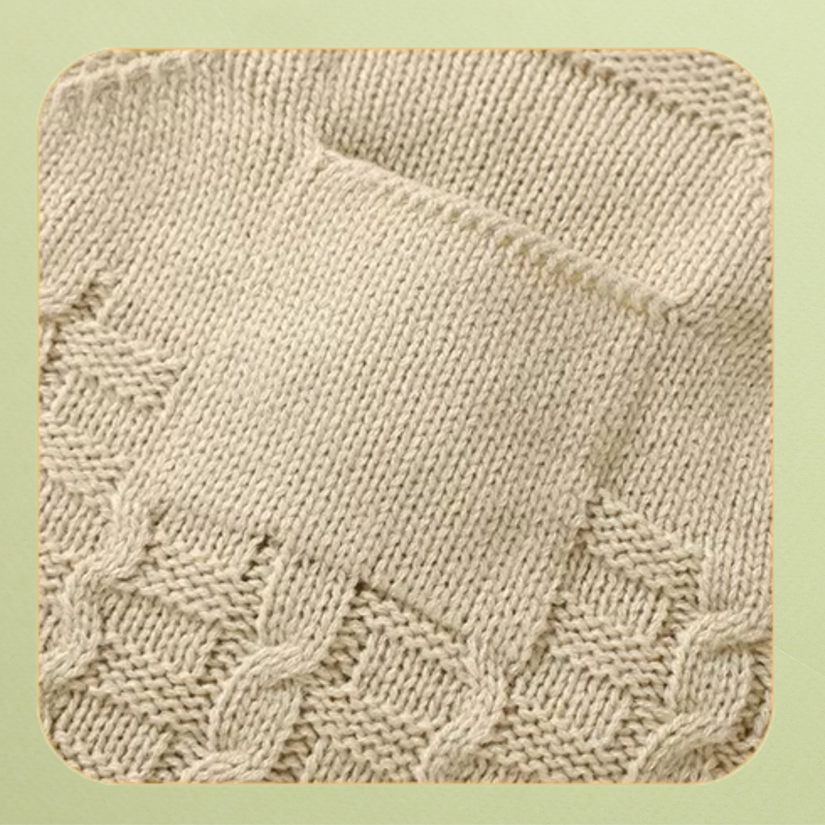 Close-up of front pocket on cream knit baby overalls with cable knit detail