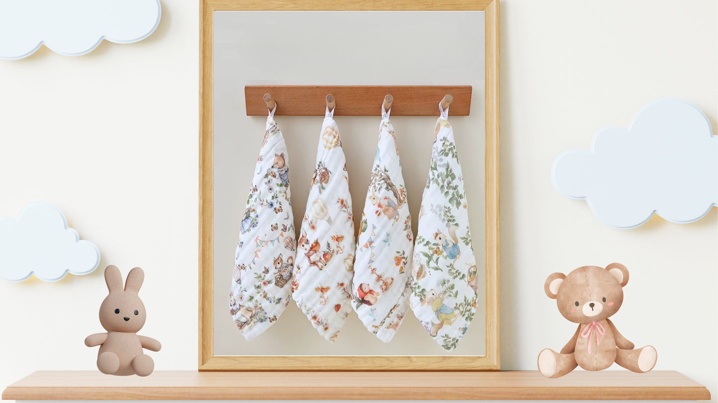 “Luxury muslin baby burp cloths in whimsical woodland prints, displayed hanging on hooks with plush bunny and teddy bear nursery decor – soft 6-layer cotton gauze gift set for newborns.”