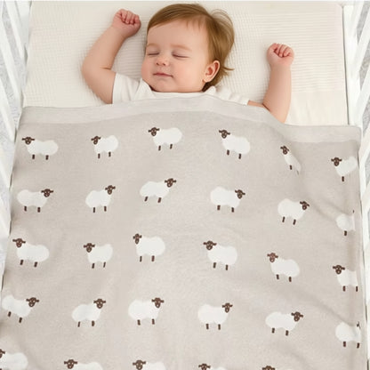 Baby sleeping under oatmeal sheep knit blanket