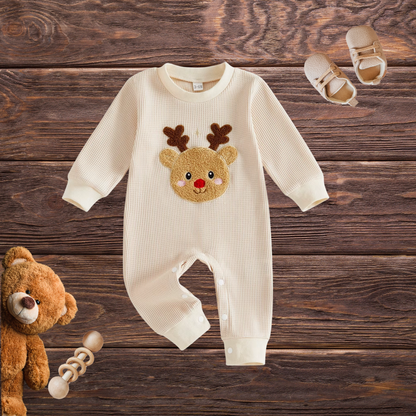 Front view of cream long-sleeve waffle-textured baby romper with raised Rudolph reindeer appliqué and snap closures, styled on a wooden background