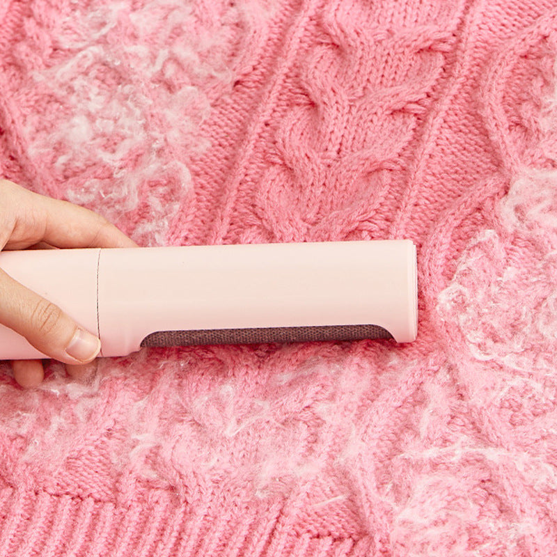 Reusable pet hair remover roller removing pet hair from a pink knitted sweater.