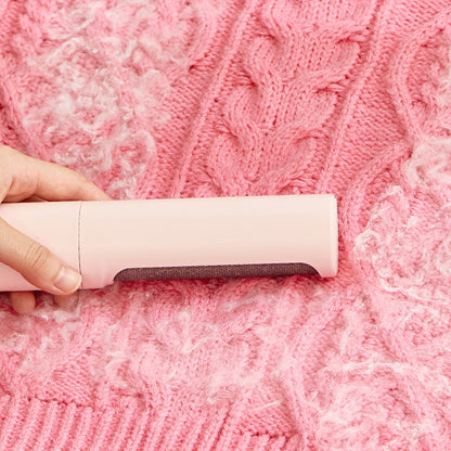 Reusable pet hair remover roller removing pet hair from a pink knitted sweater.