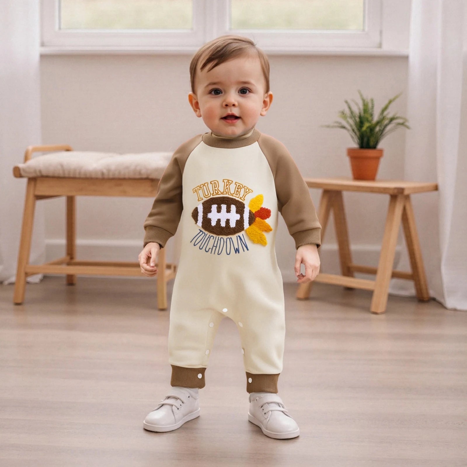 "Toddler in brown and cream romper with turkey and football print, festive fall and game day outfit"