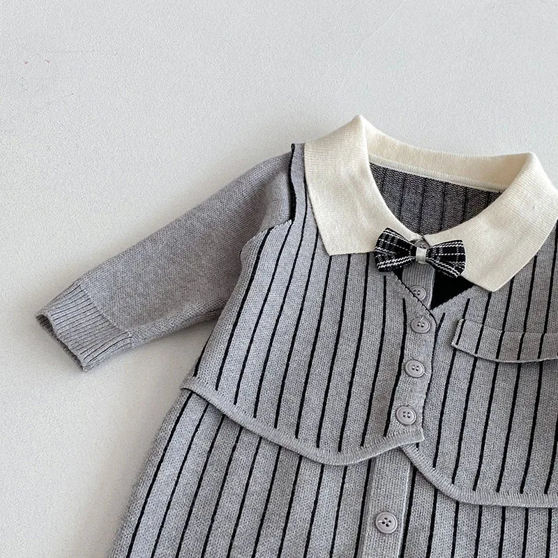 "Close-up of grey striped knit baby romper with white collar, black bow, and button details"