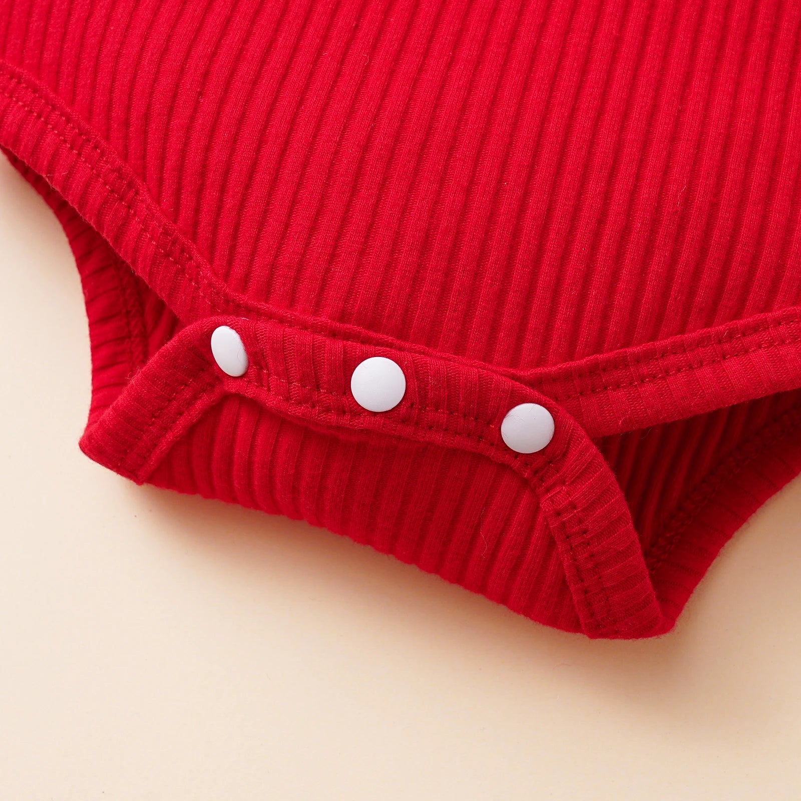 Close-up of fabric/bodysuit:
Red ribbed cotton baby romper with snap closure – holiday outfit detail.
