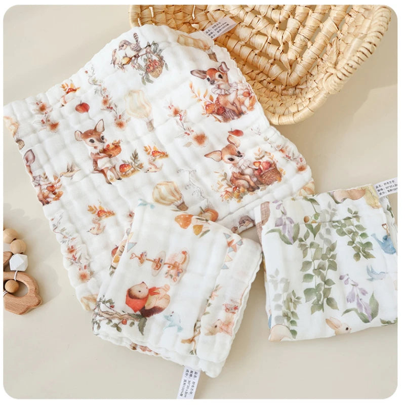 “Set of luxury muslin baby burp cloths in woodland animal and floral prints, displayed with wicker basket and wooden toy – soft 6-layer cotton gauze for newborn comfort and everyday baby care.”