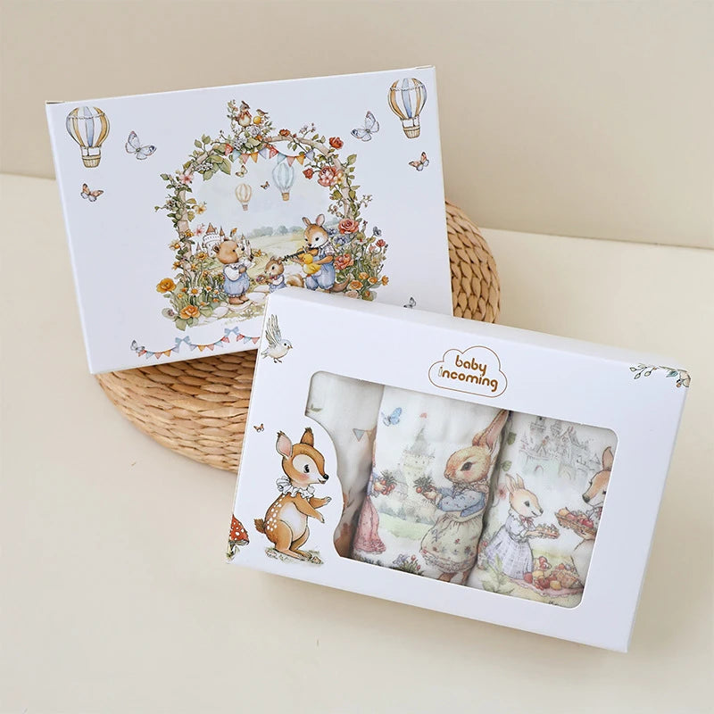 “Luxury muslin baby burp cloths gift set in whimsical woodland animal print packaging, featuring soft cotton gauze cloths presented in an illustrated keepsake box – perfect for baby showers and newborn gifts.”
