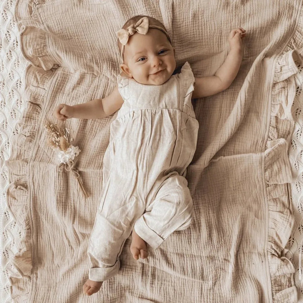 Lightweight organic muslin swaddle blanket in Sandstone, soft ruffled baby wrap, cozy neutral nursery style.