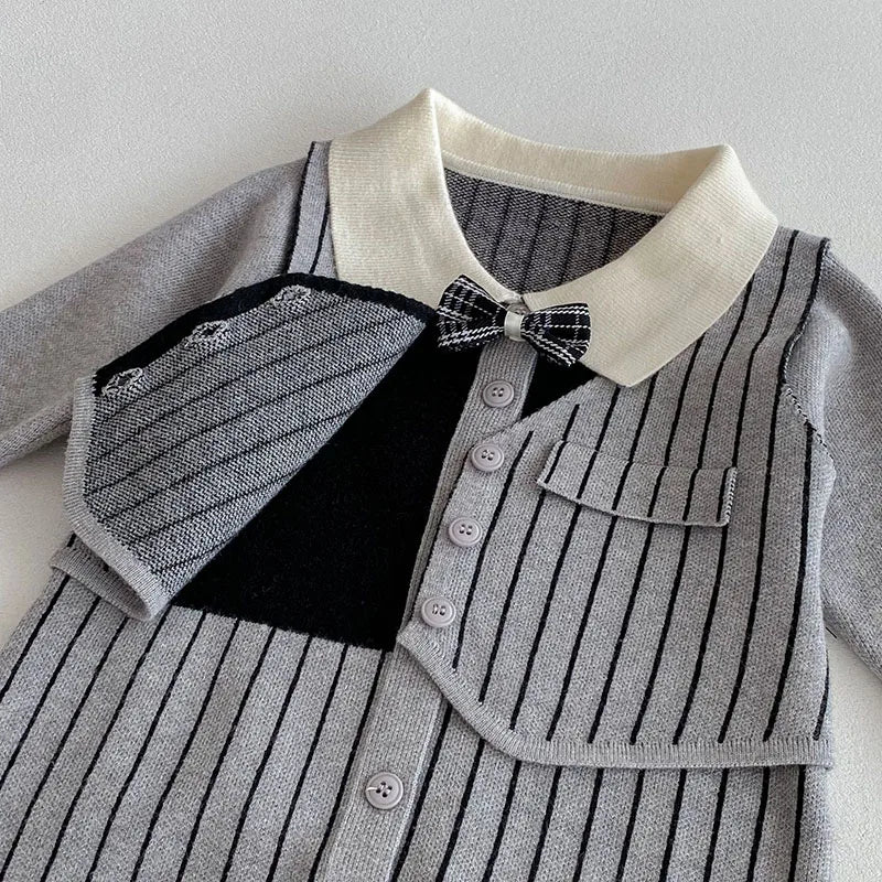 "Detailed view of striped knit fabric on baby romper with tailored buttons, collar, and bow"