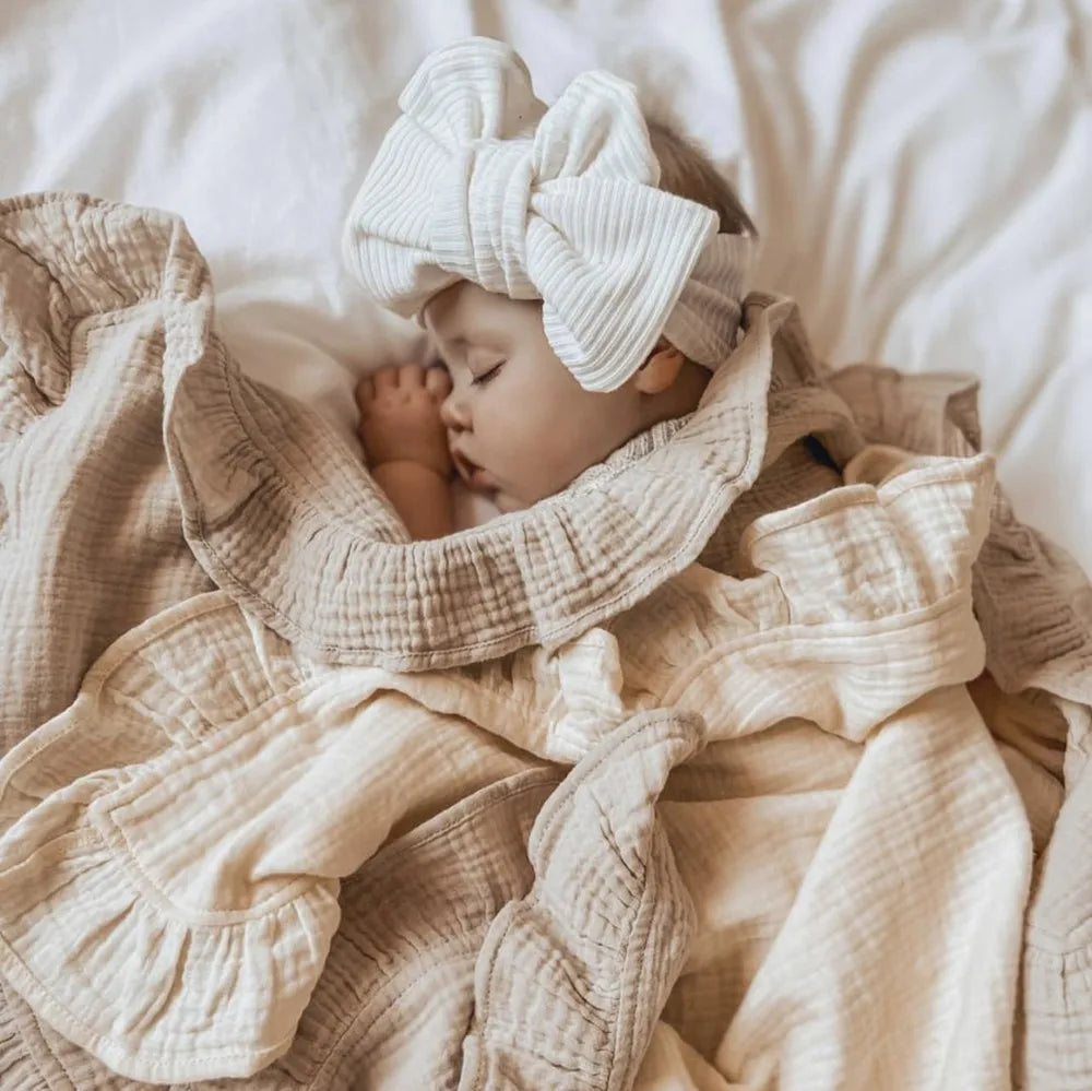Organic muslin swaddle blanket in Sandstone with soft ruffled edges, cozy newborn wrap