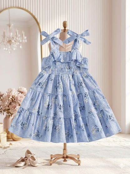 Little girl in an elegant sky blue floral ruffle dress feeding animals outdoors