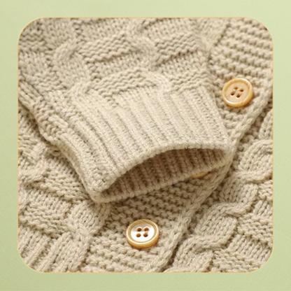 Close-up of cream knit baby cardigan ribbed cuff, cable knit texture and wooden buttons