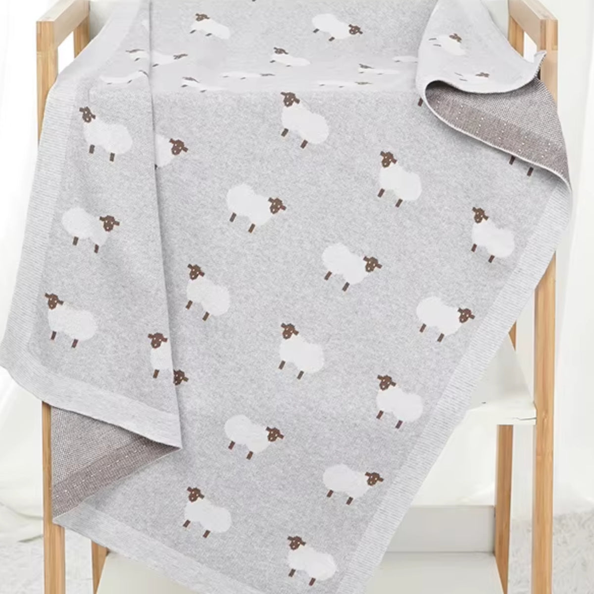 Gray sheep baby blanket draped over wooden display rack